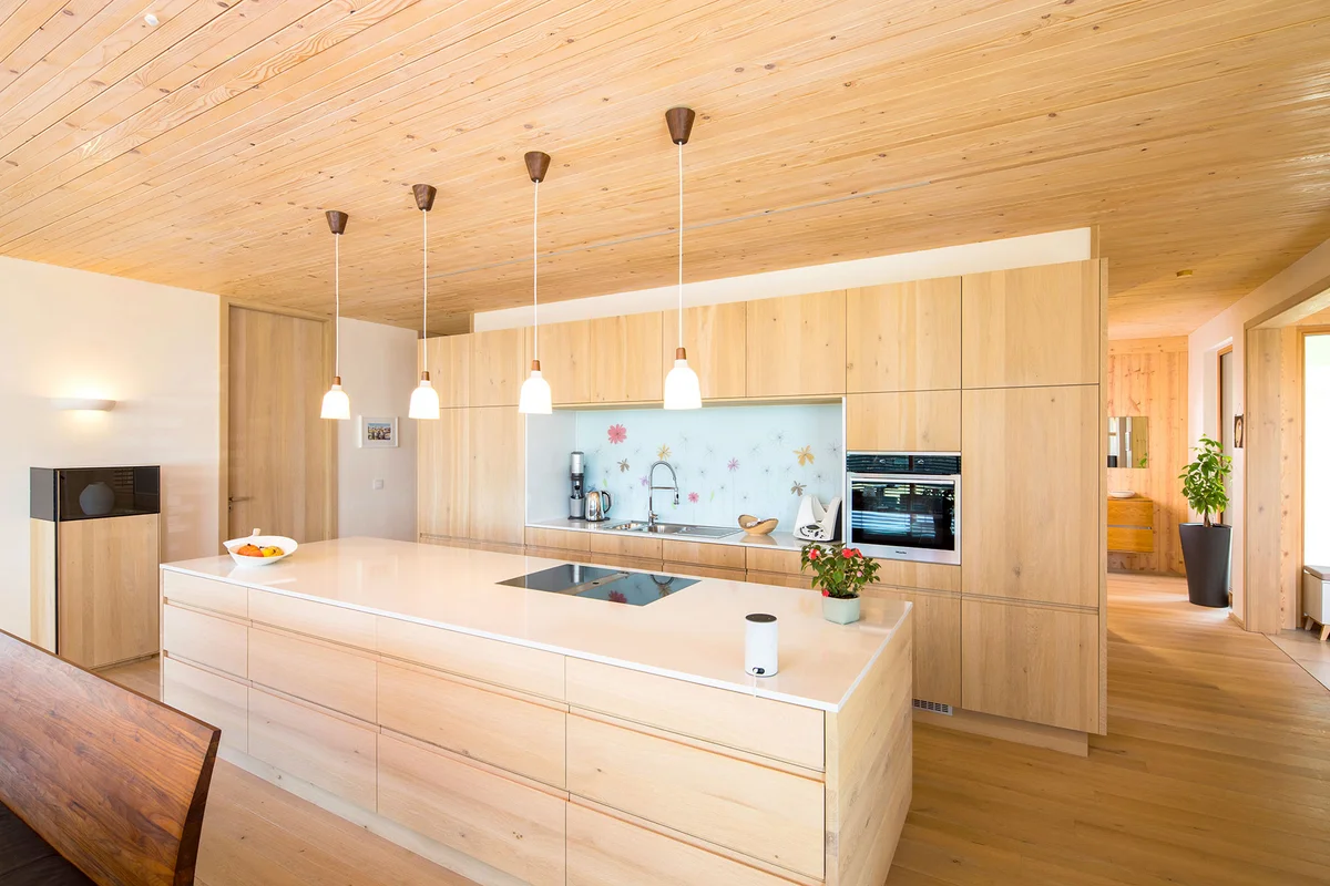 Moderne Küche mit flachen hellen Holzfronten, heller Holzdecke und Kücheninsel. © Brunthaler Naturhausmanufaktur