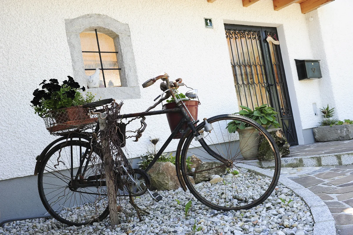 Ein altes Fahrrad mit Blumen steht als dekoratives Element vor der verputzten Fassade eines Innviertler Hofs. © Brunthaler Naturhausmanufaktur