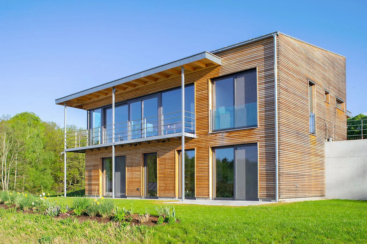 Modernes Holzhaus in Hanglage mit Übereck-Balkon und Pultdach. Die horizontal laufende Holzfassadenbretter sind unbehandelt. © Brunthaler Naturhausmanufaktur