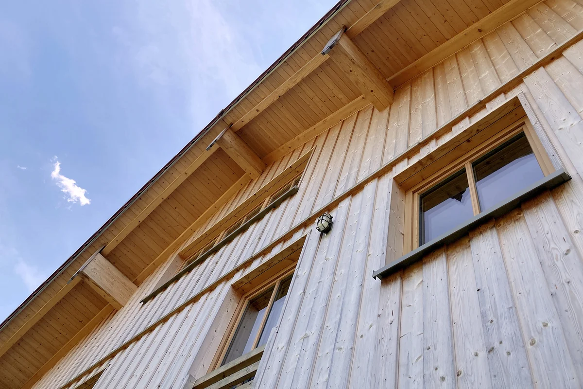 Detailaufnahme der vertikalen Holzfassade eines Massivholzhauses perspektivisch von unten. © Brunthaler Naturhausmanufaktur